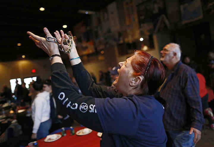 Melanie Prechel of Gahanna holds a cross and chain while singing and praying as representatives from 40 different churches gather for their monthly dinner and worship at the Upper Arlington Lutheran Church. The group was preparing for the One Night Columbus all-city worship night at the Ohio Expo Center.   (Adam Cairns / The Columbus Dispatch)